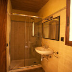 "Bany amb dutxa de vidre, lavabo i mirall il·luminat."