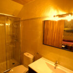 "Bany amb dutxa de vidre, lavabo i mirall il·luminat."