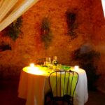 "Taula rodona amb espelmes i decoració romàntica en un ambient rústic a la terrassa."